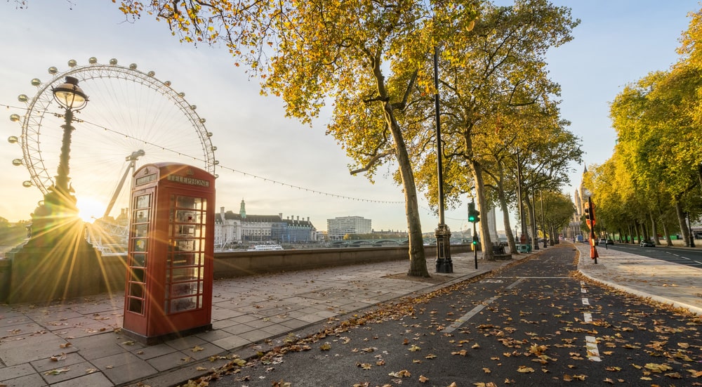 red telephone booth autumn leaves sunrise